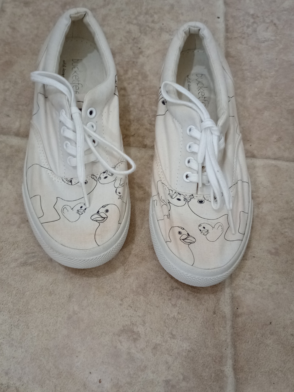BucketFeet slip-on sneakers a white canvas upper with a stick figure cartoon d